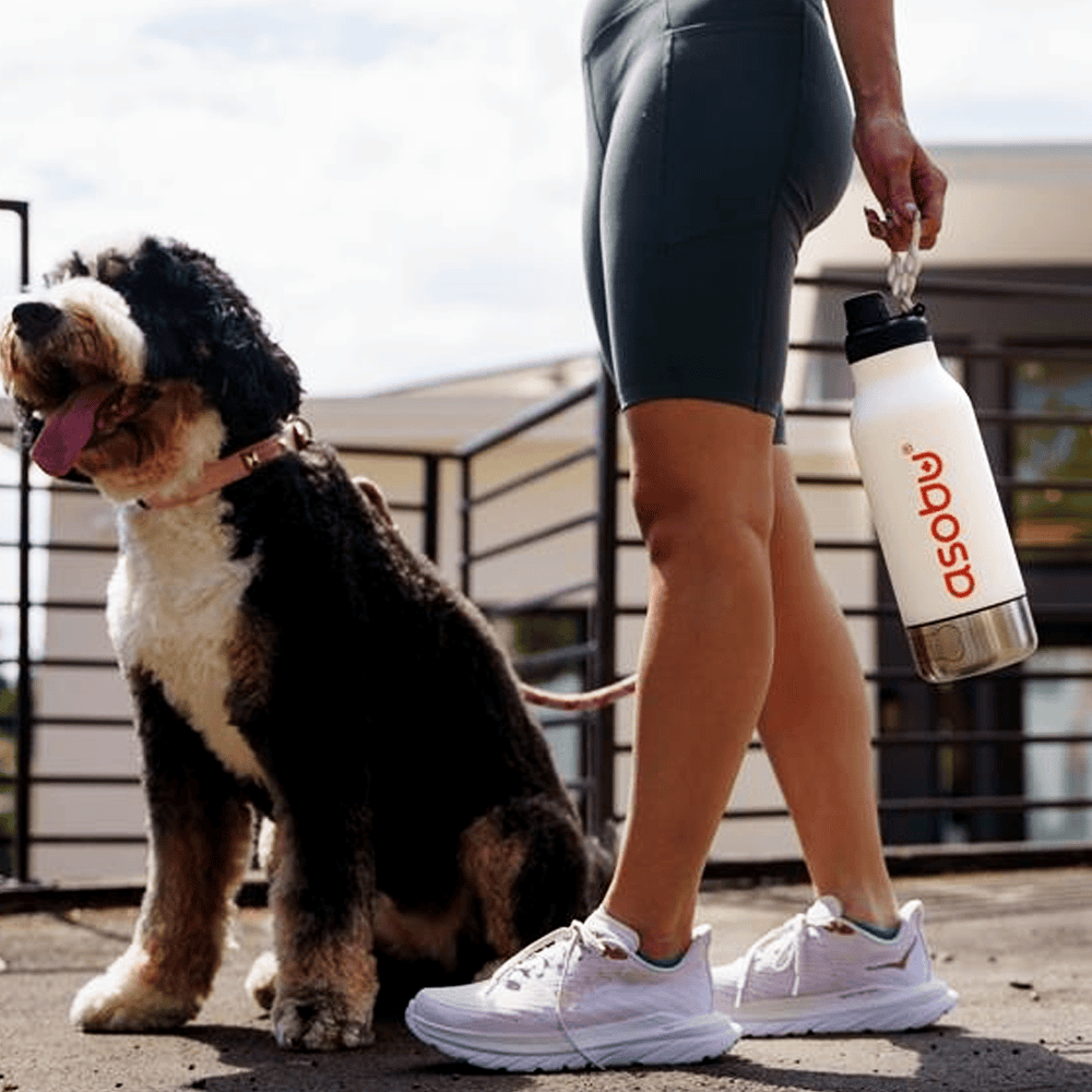 Woman with a fluffy dog, carrying an etched water bottle